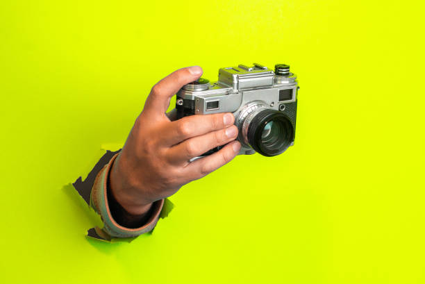 istock Vintage and retro camera in hand on yellow background 1191840665
