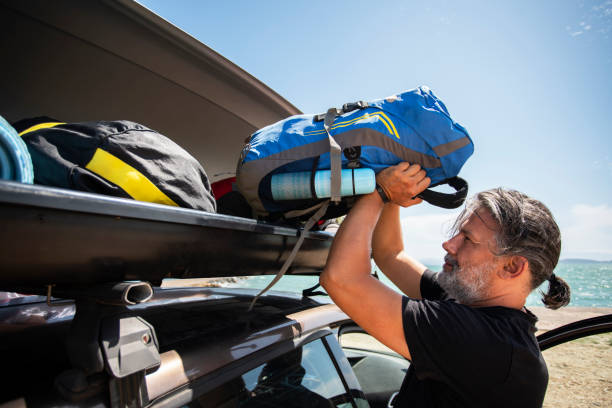 men packing cargo box container on roof rack on vacations - backpack one mature man only only mature men one man only imagens e fotografias de stock