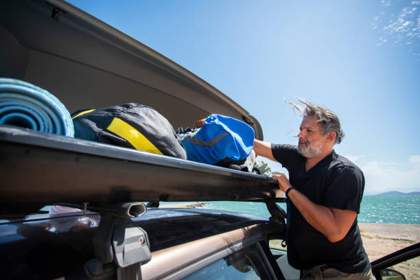 istock Men Packing Cargo Box Container on Roof Rack On Vacations 1191848166