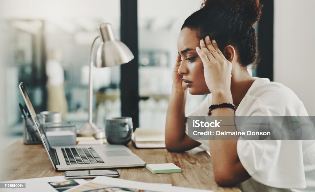 When hard work results in a headache Shot of a young businesswoman looking stressed while using a laptop in her home office Emotional Stress Stock Photo