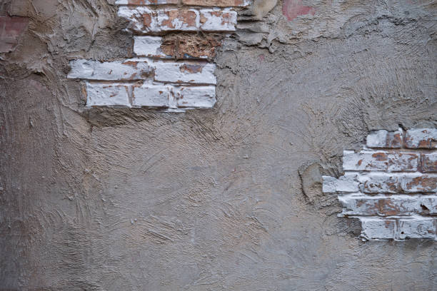 istock Background of old brick wall with dirty concrete surface, copy space for text. Texture of white ragged cement wall with brickwork 1191852061