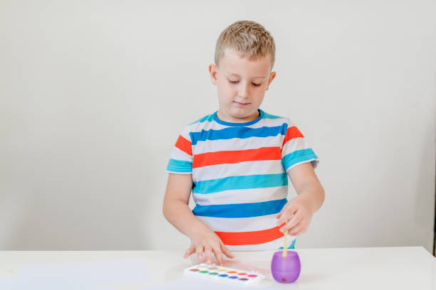 Seven years old child painting with watercolors