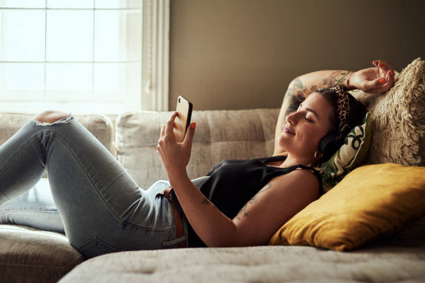 la buena música tiene el poder de relajarse - lying down women laptop freedom fotografías e imágenes de stock