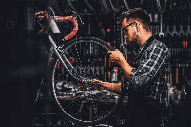 istock Attractive pensive man in protective glasses is repairing bicycle at his own workshop 1191856607