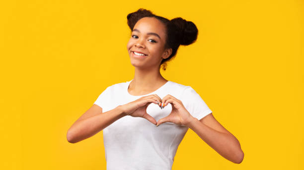 adolescente americano africano de sorriso que mostra o gesto de coração - jovem no coração - fotografias e filmes do acervo