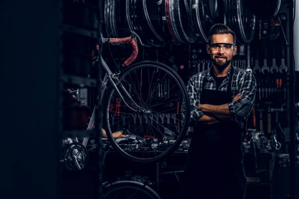 istock Handsome bearded man in glasses is standing near fixed bicycle at his own workshop. 1191857478