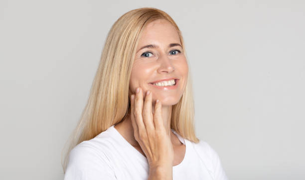 istock Morning routine. Middle-aged woman applying cream on cheek 1191857580
