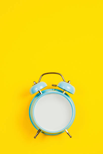 istock Vintage blue blank alarm clock on a yellow background with marskmallows as a decoration 1191858049