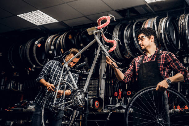 istock Two attractive mans are working on bicycle fixing at busy workshop 1191858095