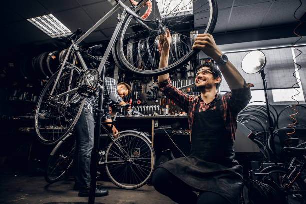 istock Two attractive repairmans are fixing broken bicycle at their dark workshop 1191858664