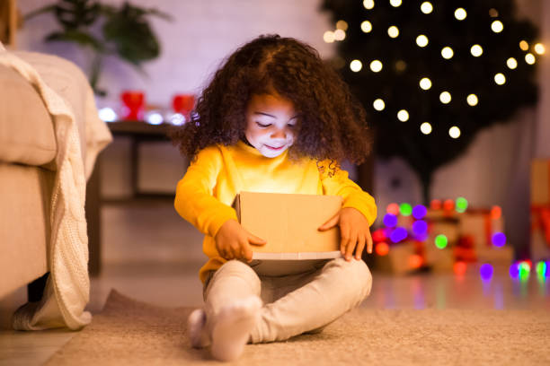 istock Amazed afro child opening glowing Xmas gift 1191858713