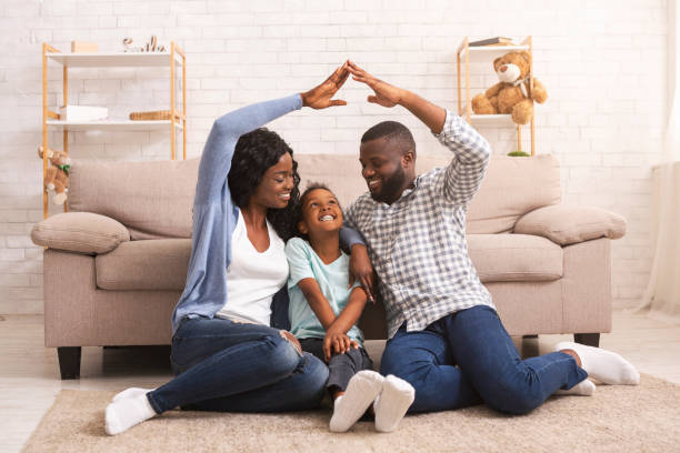 svarta föräldrar gör symboliska tak av händerna över lilla dotters huvud - security home bildbanksfoton och bilder