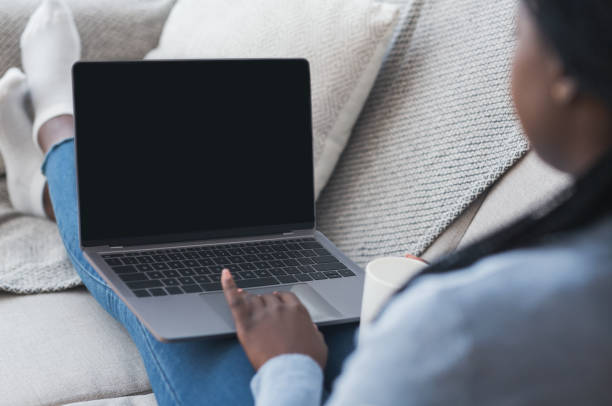 istock Woman using laptop with black screen while sitting on couch 1191858961