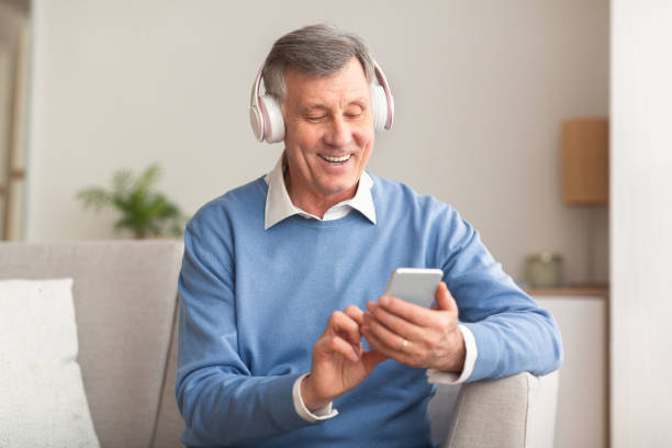 istock Elderly Man Listening To Song Using Smartphone Sitting On Couch 1191859265