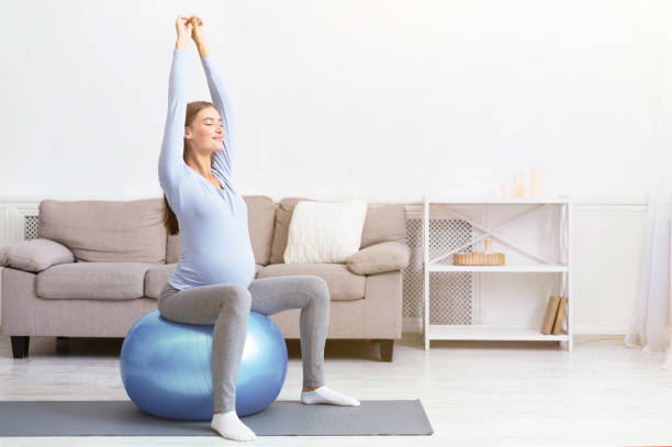 jeune fille enceinte s'asseyant sur la bille d'ajustement à la maison - yoga ball photos et images de collection