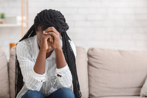 istock Desperate black girl sitting alone on sofa at home 1191860655