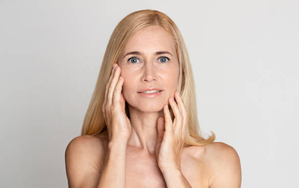 istock Beautiful middle-aged woman with bare shoulders touching her face 1191860750