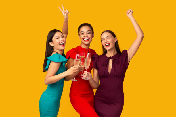 istock Three Models Clinking Glasses Having Fun Standing Over Yellow Background 1191862243
