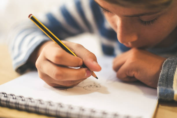 istock Midsection Of Boy Making Sketch On Book While Sitting At Home 1191862868