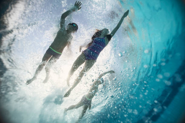 istock Happy kids swimming underwater in pool 1191865366
