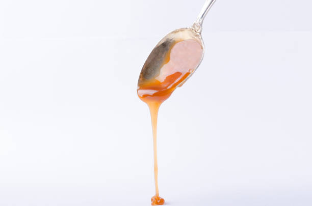 istock Melted caramel candy. Sweet topping dripping from spoon, white background 1191867805