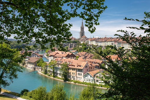 Panorama view of Berne old town from mountain top in rose garden. \nChurch, bridge and houses with tiled rooftops, Bern, Switzerland stock photo.\n\nBern, the capital city of Switzerland, is built around a crook in the Aare River. It traces its origins back to the 12th century, with medieval architecture preserved in the Altstadt (Old Town). The Swiss Parliament and diplomats meet in the Neo-Renaissance Bundeshaus (Federal Palace). The Französische Kirche (French Church) and the nearby medieval tower known as the Zytglogge both date to the 13th century.