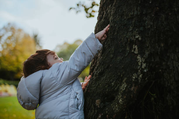 istock Cute Baby Girl Touching Tree In Park 1191869051