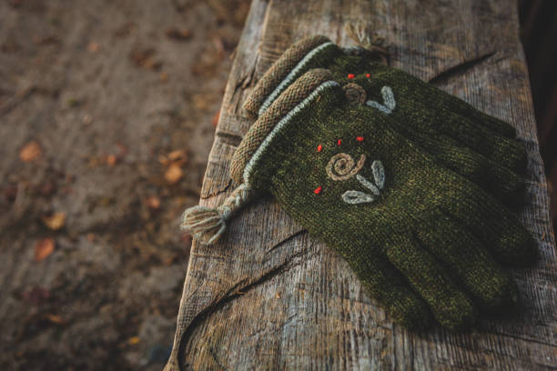 Knitted woolen gloves laying on a wooden bench in autumn concept of forgotten object, personal item. Perhaps portraying loneliness, independence, walking and activity.