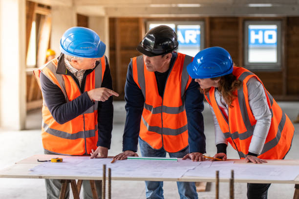 istock Foreman and forewoman discussing blueprint with architect 1191873159