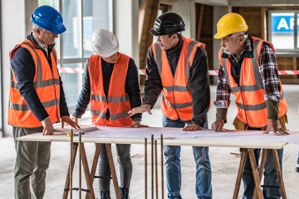 istock Foreman and forewoman discussing blueprint with male architect at construction site 1191873176