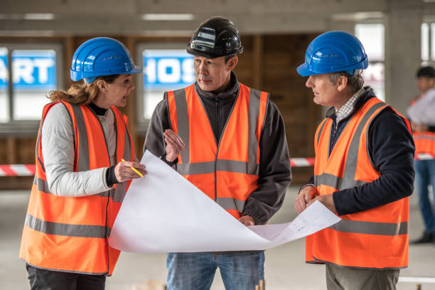 istock Foreman and forewoman discussing blueprint with architect 1191873184