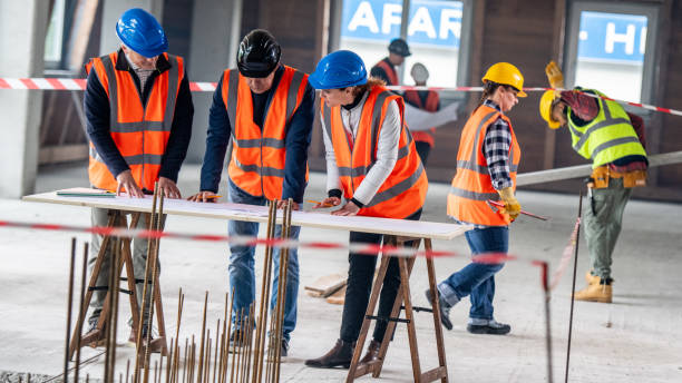 istock Foreman and forewoman discussing blueprint with architect 1191873199