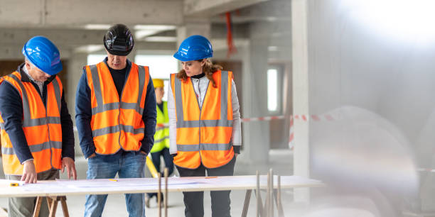 istock Foreman and forewoman discussing blueprint with architect 1191873238