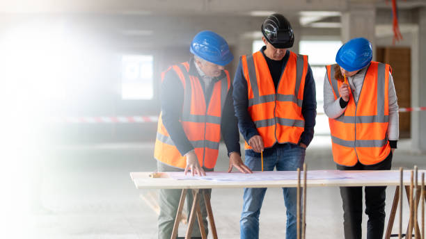 istock Foreman and forewoman discussing blueprint with architect 1191873257