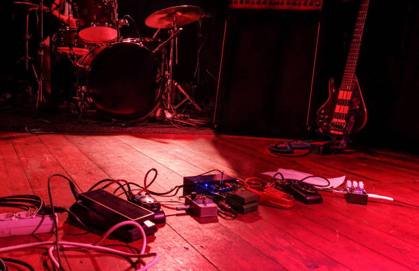 rot gefärbter stimmungsvoller bühnenraum mit musikinstrumenten - guitar pedal stock-fotos und bilder