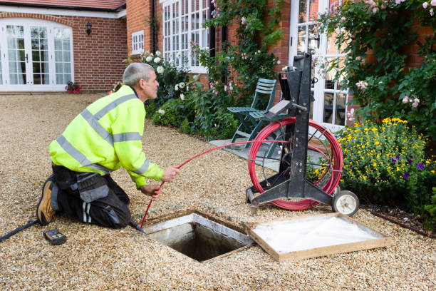 Man unblocking outside drain BUCKINGHAM, UK - October 16, 2019. A professional drain cleaning engineer inspects a blocked household drain sewer photos stock pictures, royalty-free photos & images