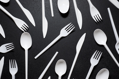 Disposable plastic cutlery on a black table.