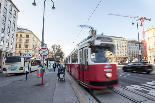 Picture of a tram of Vienna, Austria, on the tramway tracks of the city center, with an old woman walking nearby. Trams in Vienna , also called Wiener Straßenbahn, or Bim or Tramway, are a vital part of the public transport system in the capital city of Austria.