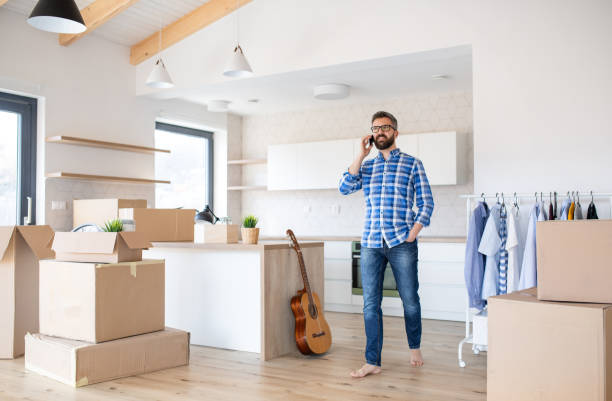 istock Mature man with boxes moving in new house, using smartphone. 1191880051