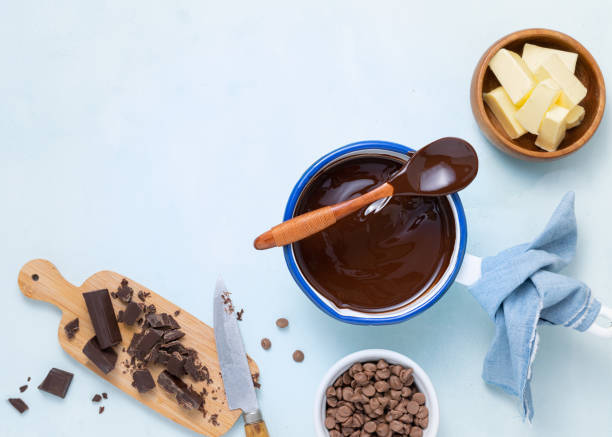 Molten chocolate with different types of chocolate for dough preparation recipe chocolate ganache, cake, brownie, muffins, cupcakes ingridients, food flat lay on light background. Text space.