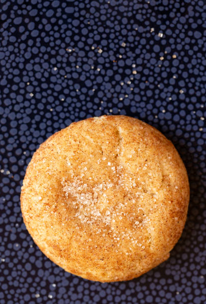 One snickerdoodle cookie  on a blue surface Overhead view of one freshly baked snickderdoodle cookie on a deep blue surface round sugar cookie stock pictures, royalty-free photos & images