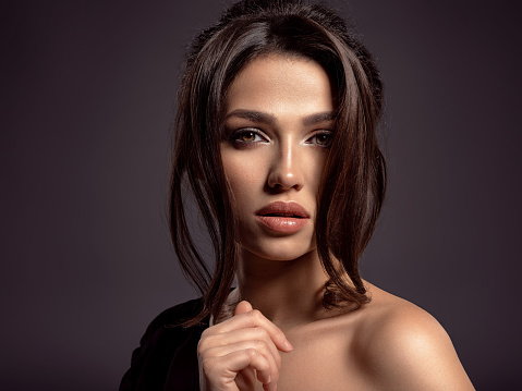 Beautiful woman with brown hair. Attractive model with brown eyes. Fashion model with a smokey makeup. Closeup portrait of a pretty woman looks at camera. Beautiful woman.