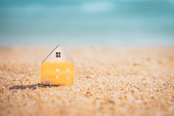 istock Small home model on sunset beach sand texture background. 1191884186
