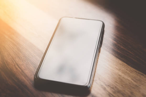 istock Smart phone on wooden table with sun light window at cafe. 1191884270