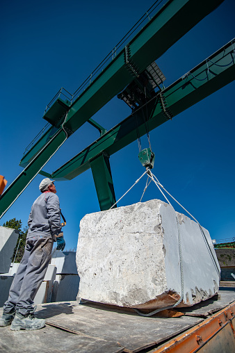 Adult Man Using Crane To Load Heavy Block Shape Marble.