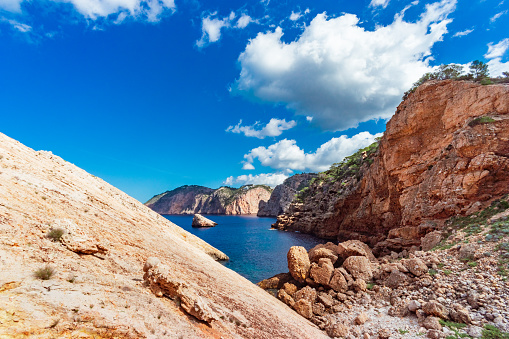 View of the typical landscape of the northern coast of Ibiza, near the cove of Es Portitxol, picturesque clouds, steep rocky cliffs, deep blue sea. Developed from RAW.