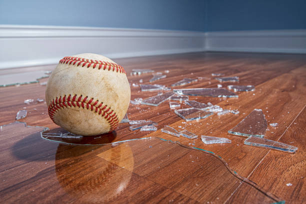 istock A low angle view of a baseball with broken glass from a window on the floor 1191888670