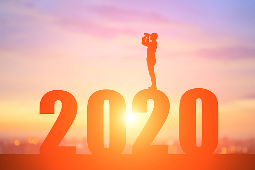 silhouette of business man look through Binoculars with 2020