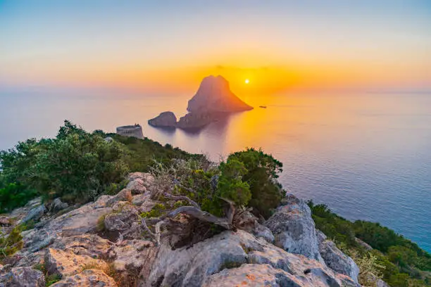 View of the rocky isles of Es Vedrà and Es Vedranell, and Torre des Savinar (a.k.a. Torre del Pirata), off the south-west coast of Ibiza, a golden sunset for one of the most stunning, iconic panoramas of the island. Developed from RAW.