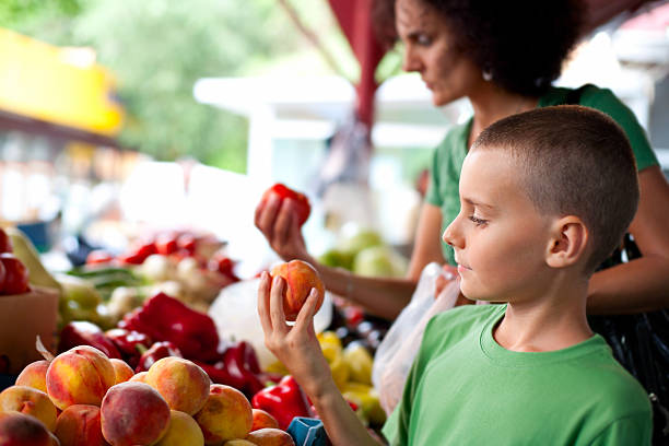 carino ragazzo e sua madre presso il farmer's market - market farmers market agricultural fair child foto e immagini stock